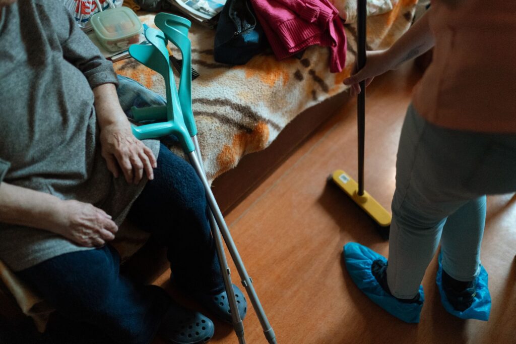 Opiekunka pomaga seniorce w domowych porządkach